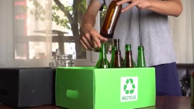 Bir adam renk ile ayrılmış geri dönüştürülebilir cam bertaraf: kahverengi, yeşil ve beyaz