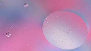 Suda makro yağ düşüşü. Pembe ve mavi pastel renkler. Degrade sıvı