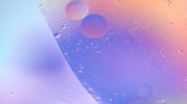 Suda makro yağ düşüşü. Pembe, mor, pastel neon renk kabarcıklar. Gerçek holografik sıvı