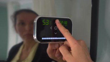 Modern merkezi ısıtma kontrolü zamanlayıcı ve termostat birleştirmek, set sıcaklıkları. Bir kadın su ısıtıcı sıcaklığını ayarlar