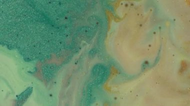 Pastel turkuaz parlak inci sıvısı kozmetik ürünleri bej sarısı boya ile karıştırılır ve akar. Sihirli hareket makro fotoğrafçılık. Parlak arkaplan dokusu