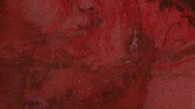 Koyu kırmızı ve Burgundy parlak sıvı kaynıyor. Hareketli Parıltılı Boyalar. Soyut arkaplan