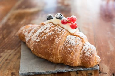 Mascarpone ile dolu ve kızılcık ve kuş üzümü ile süslenmiş kruvasan