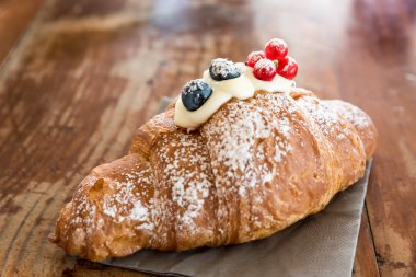 Mascarpone ile dolu ve kızılcık ve kuş üzümü ile süslenmiş kruvasan