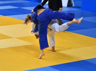 Kimonolu iki kız judoka tatamide yarışıyor.