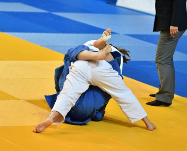 Kimonolu iki kız judoka tatamide yarışıyor.