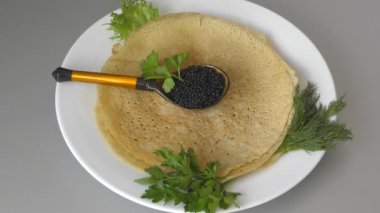 Siyah havyarlı krepler ve taze otlar. 