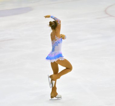 Kız artistik buz pateni pistinde suni buz ile yuvarlanıyor.