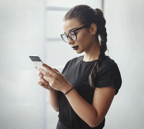 Gözlük ve siyah ruj cep telefonu tutan genç esmer kızla