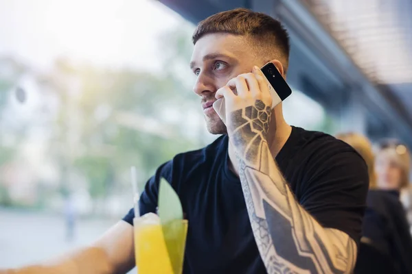Atrakcyjny Młody Człowiek Tatuażem Trzyma Telefon Komórkowy Picia Świeżą Lemoniadę — Zdjęcie stockowe