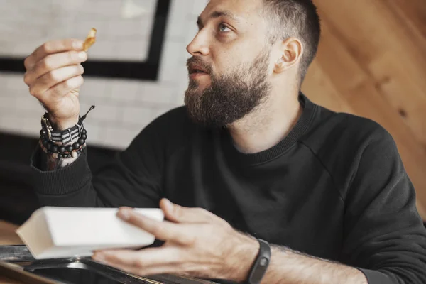 Joven barbudo comiendo papas fritas de cerca . — Foto de Stock