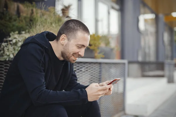 Hombre barbudo mirando la pantalla del teléfono móvil y sonriendo . — Foto de Stock