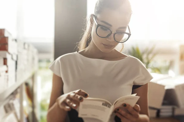 Młoda atrakcyjna kobieta zamyślony czytania książki w księgarni. Widok z przodu — Zdjęcie stockowe