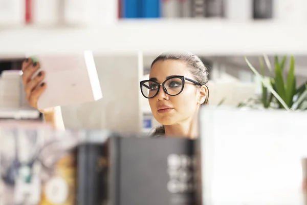 Młoda brunetka kobieta wybierając książki w księgarni. — Zdjęcie stockowe