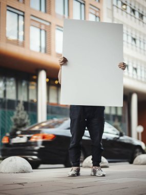 Genç çekici holding boş tuval Street kırmızı binanın yanındaki adam.