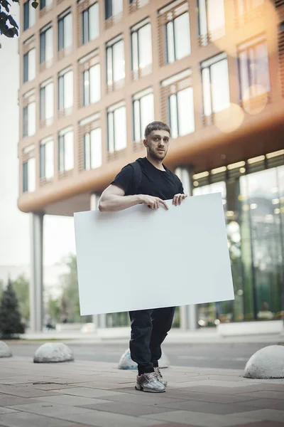 Jovem segurando tela em branco horisontalmente e olhando para o espectador . — Fotografia de Stock