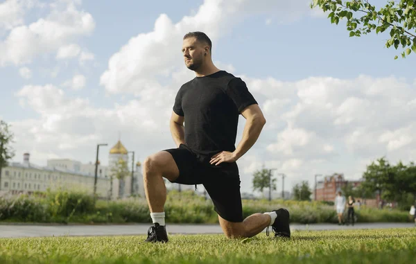 Jeune homme attrayant faisant lunge en plein air . — Photo