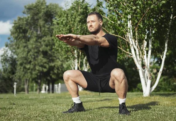 Jeune homme attrayant accroupi en plein air dans le parc. — Photo