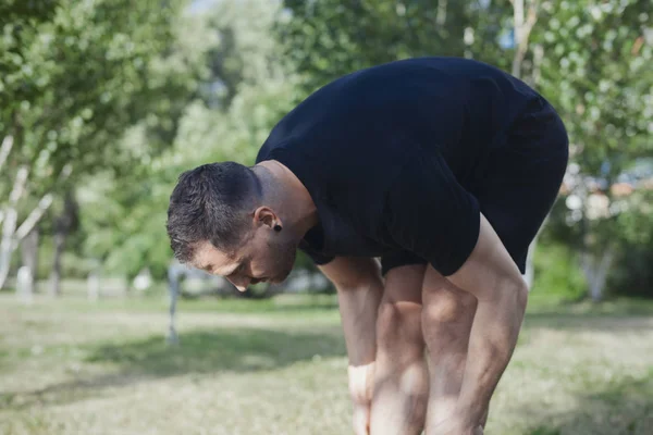 Homme attrayant faisant des exercices d'étirement à l'extérieur dans le parc . — Photo