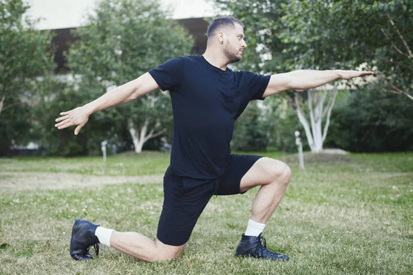 Joven hombre atractivo haciendo embestida al aire libre en el parque con las manos extendidas . — Foto de Stock