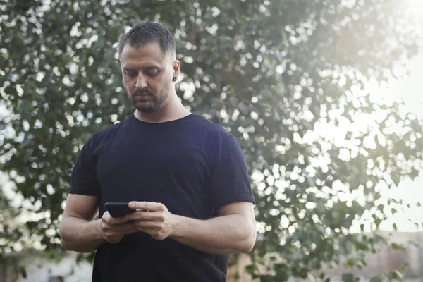 Jovem digitando mensagem de texto no celular ao ar livre no parque . — Fotografia de Stock