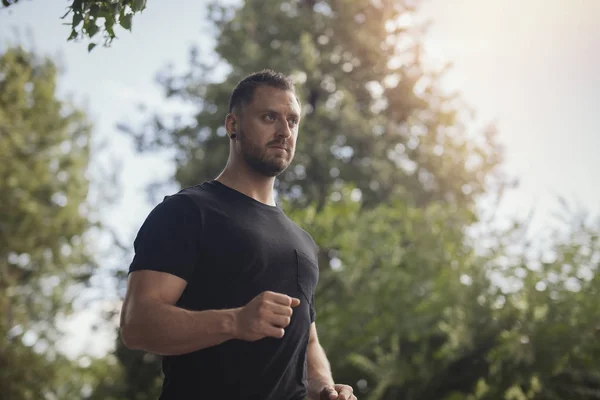 Jeune homme courant à l'extérieur dans le parc . — Photo