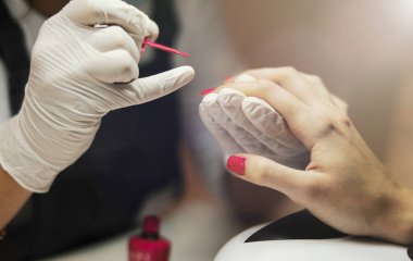 Boya çivi kırmızı oje ile yakın çekim manikür ustası.