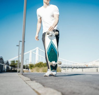 Genç çekici adam holding longboard.