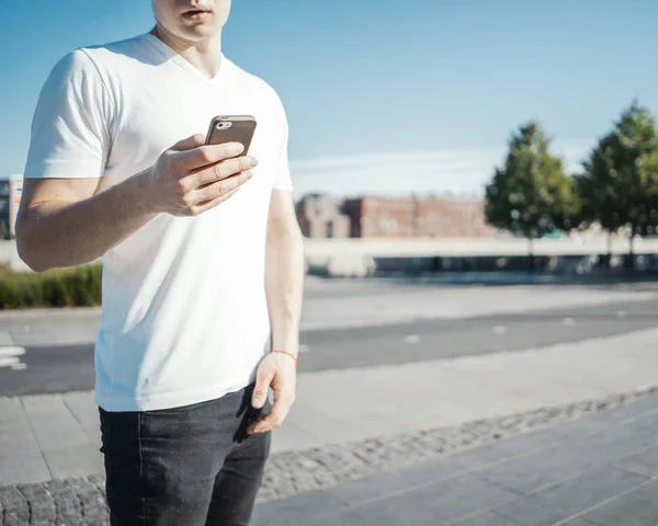 Jovem homem atraente segurando telefone celular na mão direita . — Fotografia de Stock