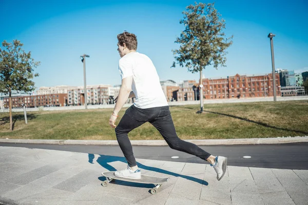 Fiatal, vonzó férfi lovaglás longboard a parkban. — Stock Fotó