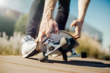 Çekici gencin parkta longboard sürme yakın çekim.