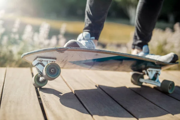 Primer plano del joven atractivo montando longboard en el parque . —  Fotos de Stock