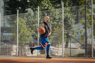 Basketbol oynarken kel çekici adam.