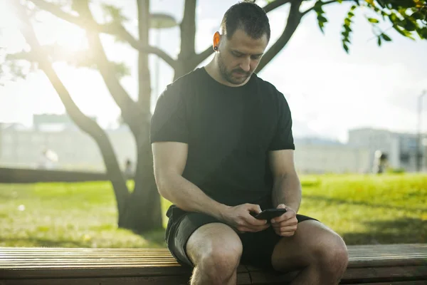 Gros plan du jeune homme tapant un message texte sur son téléphone portable dans le parc . — Photo