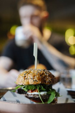 Taze büyük lezzetli burger Cafe arka plan üzerinde adamla yakın çekim.