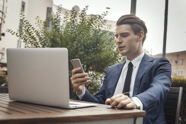 Młody atrakcyjny biznesmen trzymając telefon komórkowy w ręku. — Zdjęcie stockowe