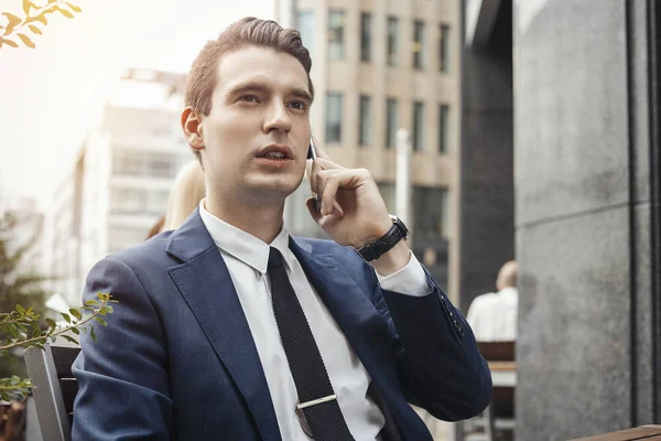 Jovem empresário morena falando por telefone celular e olhando em linha reta . — Fotografia de Stock