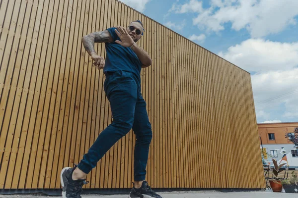 Młody człowiek z niebieski dredy tańca reggaeton na ulicy. — Zdjęcie stockowe