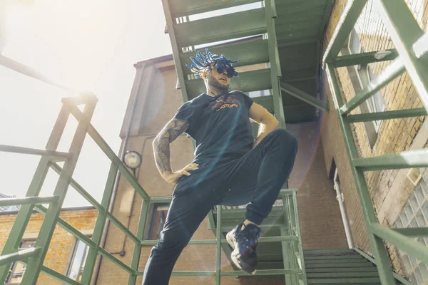 Młody człowiek z niebieski dredy tańca reggaeton na schodach zielony. — Zdjęcie stockowe