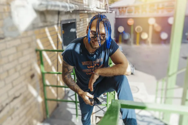 Joven con rastas azules de pie en escaleras verdes . —  Fotos de Stock