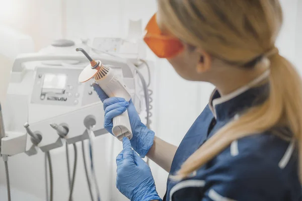 Primer plano de la mujer dentista en azul uniforme de control de equipos dentales . — Foto de Stock