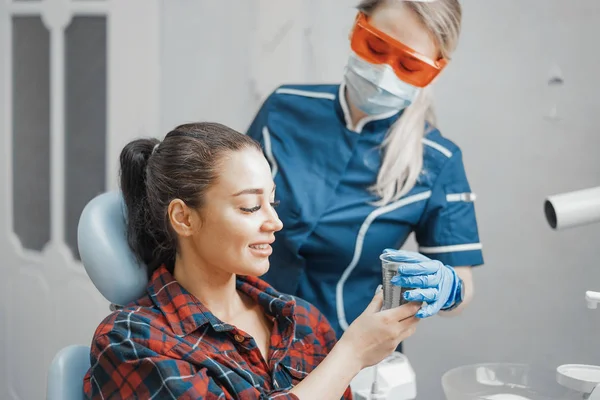 Primer plano de la mujer dentista dando taza de plástico con agua a un cliente  . — Foto de Stock