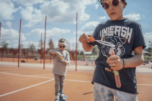 Primo piano di skateboading e fare bolle ragazzi al parco giochi colorato . — Foto Stock