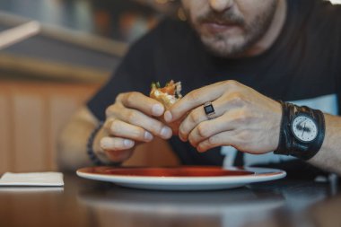 Genç adam yeme hamburger ve patates kızartması kafede kapatın. Önden görünüm.