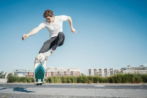 Joven hombre atractivo montar y saltar longboard en el parque . —  Fotos de Stock