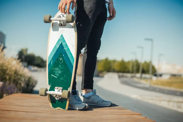 Close up of young man holding longboard or skateboard in the park. — Stock Photo, Image