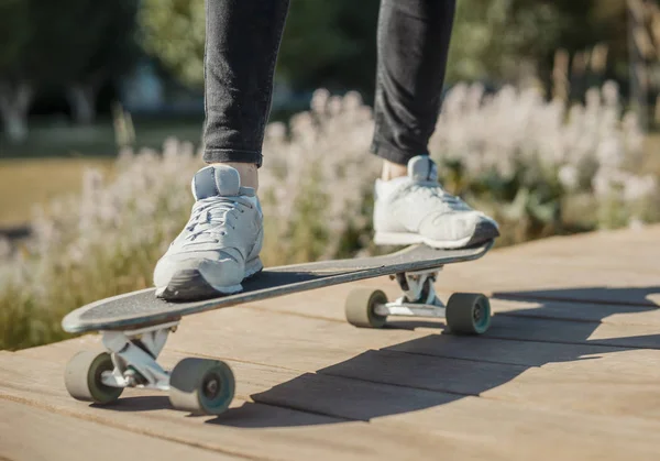 Primer plano del joven en zapatillas de deporte montando longboard o monopatín en el parque . —  Fotos de Stock