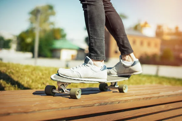 Nahaufnahme eines jungen Mannes in Turnschuhen, der im Park Longboard oder Skateboard fährt. — Stockfoto