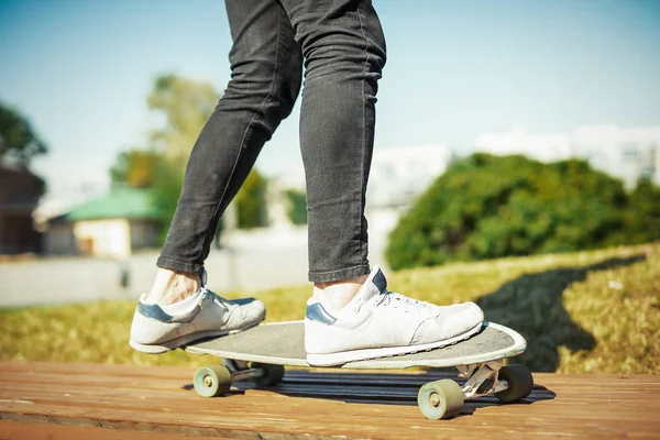 Nahaufnahme eines jungen Mannes in Turnschuhen, der im Park Longboard oder Skateboard fährt. — Stockfoto