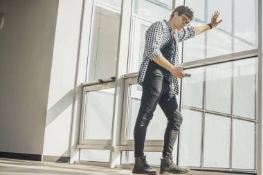 Genç adamın cep telefonu ekran metro istasyonunda bakarak uzak planı.